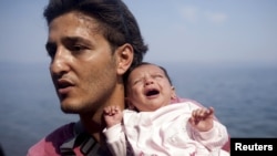 A Syrian refugee from Aleppo holds his 1-month-old daughter moments after arriving on a dinghy on the Greek island of Lesbos on September 3.
