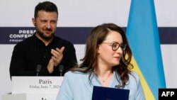 Președintele Zelenski aplaudă la o ceremonie de semnare de documente la Paris, în iunie, de către ministra Economiei, Iulia Sviridenko. Ea ar urma să devină prim-ministră.