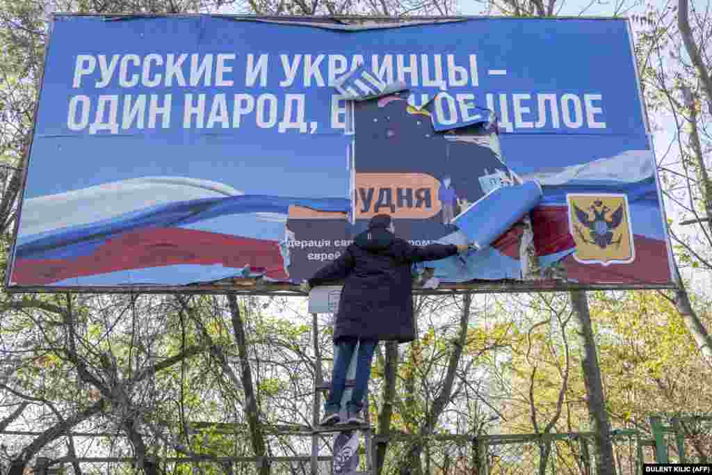 A banner that states "Russians and Ukrainians are one people, one whole" is torn down in the newly liberated city of Kherson on November 14. Kherson's residents are facing shortages of electricity and water as winter looms.