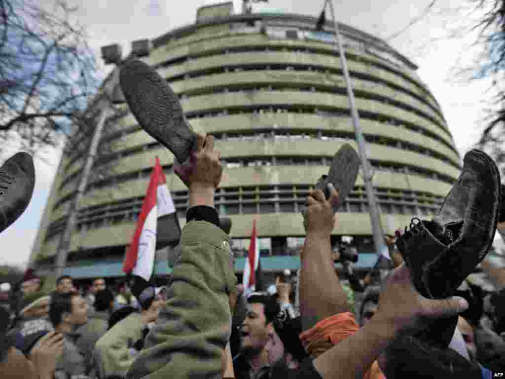 Antigovernment protestors demonstrate by raising their shoes in front of state TV in Cairo on February 11.