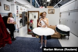 Një rrobaqepëse duke rregulluar kostumin e Muromtsevas në prapaskenë.