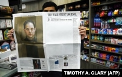 Un vânzător de ziare din New York arată un exemplar din 29 martie 2024 al cotidianului The Wall Street Journal, care prezintă o primă pagină aproape goală, pentru a marca împlinirea unui an de la încarcerarea în Rusia a reporterului lor Evan Gershkovich.