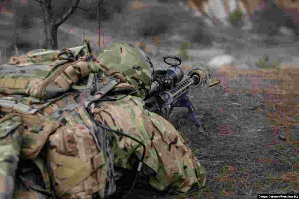 În timpul antrenamentului, un cursant trage un foc de armă. Elanski spune că mulți foști lunetiști din Ucraina au fost recalificați pentru a opera drone FPV (first-person view) înarmate, dar el afirmă că trăgătorii de elită mascați sunt încă de neînlocuit pe câmpul de luptă. &bdquo;Dronele nu pot zbura pe ploaie torențială", spune instructorul, în timp ce "lunetiștii pot trage pe orice vreme&rdquo;.