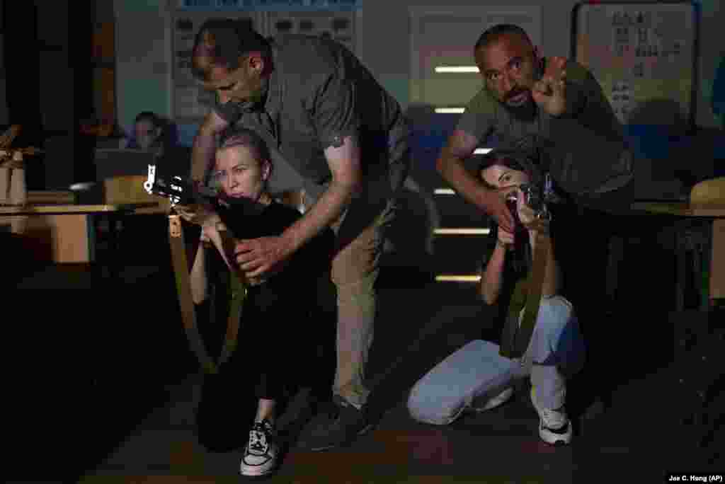 Dy gra me pushkë AK-47 të improvizuara duke ushtruar se si të gjuajnë me armë zjarri, gjatë një trajnimi në Kiev më 11 korrik. Autoritetet në kryeqytet po ofrojnë trajnime për mësimin e shkathtësive të mbijetesës për qytetarët, duke përfshirë edhe si të gjuajnë me armë zjarri, të japin ndihmën e parë mjekësore dhe t'i dallojnë minat në tokë.