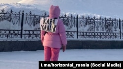 Женщина, с прикрепленной к спине надписью «кара халык» или «простой народ». Увая, 19 января 2024 года.