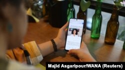 یک زن در کافه‌ای در تهران در حال خواندن خبر برنده شدن نرگس محمدی