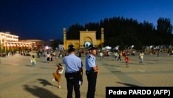 Шинжаң аймагындагы Кашкар шаарынын башкы аянтында күзөттө турган полиция кызматкерлери. 2023-жылы 15-июлда тартылган сүрөт.