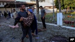 Газадагы ооруканада болгон жардыруудан жабыркаган аялды көтөрүп бараткан жергиликтүү тургун. 17-октябрь, 2023-жыл.