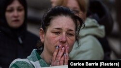 O femeie privește corpurile scoase de sub dărâmăturile unui bloc distrus de o rachetă rusească, în orașul Uman, regiunea Cerkasîi, Ucraina, 28 aprilie 2023.