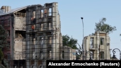 A construction crew works on what remains of a building in Russian-occupied Mariupol, Ukraine, August 16, 2023.