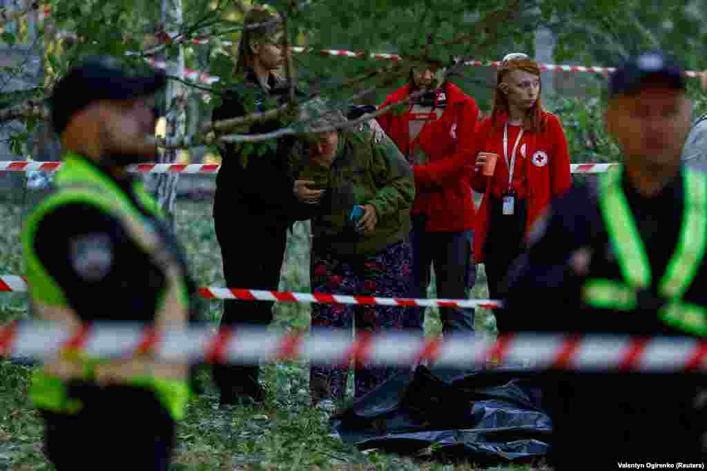 The woman is comforted by emergency responders at the scene. Lyudmyla, a local resident who declined to provide her surname said, &ldquo;Everything happened very fast, within probably 15 minutes: the air-raid siren, then the air-defense forces fired, then a cloud of brown smoke."