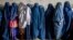 Afghan women wait to receive food rations distributed by a humanitarian aid group in Kabul in May 2023. 