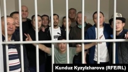 Кемпир-Абад ишине айыпталып камалган саясатчы, активист жана коомдук ишмерлер. Булардын ичинен Атай Бейшенбек (алдыңкы катарда, ортодо) 23-июнда соттун чечими менен үй камагына чыккан.