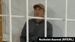 Askat Jetigen sits in a defendants' cage in a courtroom on May 23.