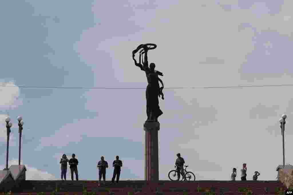 Residents watch the partially flooded area as waters rise in Kherson.