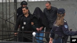 Cu capul acoperit, adolescentul care a ucis opt elevi este escortat de poliție în fața școlii primare Vladislav Ribnikar din Belgrad, pe 3 mai.