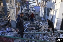 Palestinieni caută printre dărâmăturile unei clădiri în urma unui bombardament israelian la Rafah, în sudul Fâșiei Gaza, pe 26 decembrie 2023.