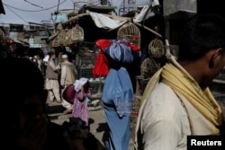 Базар аралап жүк көтөрүп бараткан оогандык аял жана кичинекей кыз.