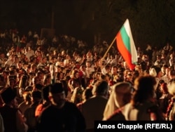 Bir adam ot ýakylmazdan öň Bolgariýanyň baýdagyny galdyrýar.