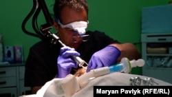 Врач Александр Туркевич убирает с лица ребенка пороховые ожоги во Львове. Украина, 2024 год