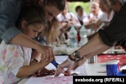 Маці з дачкой размалёўваюць ручнік традыцыйнымі ўзорамі праз шаблён, фэстываль «Сонцаграй», чэрвень 2023