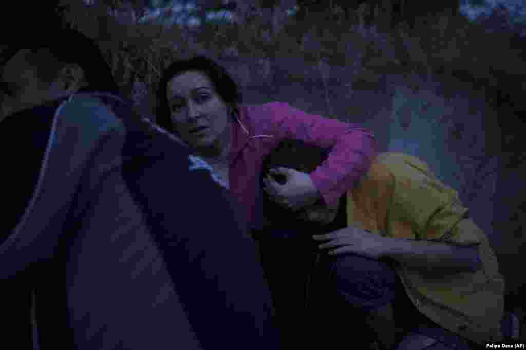 Iryna Sokeryna holds her daughter Lyubov as they take cover from Russian shelling while being evacuated from a flooded neighborhood in Kherson.