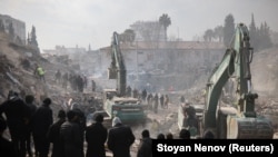 Люди наблюдают, как продолжаются поиски выживших после смертоносного землетрясения в Кахраманмараше, Турция, 10 февраля 2023 года.