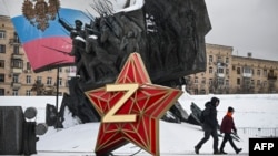 Хора преминават покрай кремълска петолъчка с буквата Z, емблема на руските агресори в Украйна, на фона на паметник на героите в Първата световна война. Москва, 26 декември 2023 г.