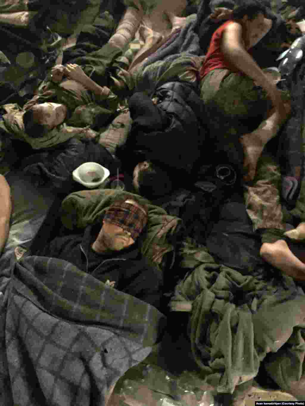 Azovstalniñ bomba sığınalarından birinde arbiy gospital. Asannıñ aytqanına köre, bazıda mında yaralanğanlarnıñ sayısı beş yüz insanğa yetken edi: "Qan, kesilgen ayaq-qol, irin, necaset, sidik, teri... ve büyük dımlıq. Çünki eñ az 300 insan aynı vaqıtta bir odada, büyük bir mağazda nefes ala"