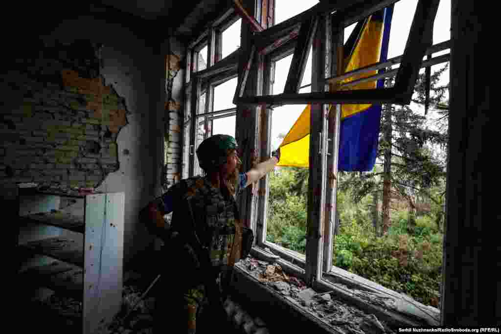 "Борода" расправляет вывешенный из окна Дома культуры Благодатного украинский флаг, символ освобождения поселка