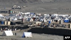 له پاکستان افغانستان ته اوښتي کډوال د نومبر پر ۱۲مې د خپلو خیمو مخې ته ناست دي. 