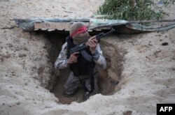 Un luptător palestinian din Brigăzile Naționale de Rezistență, aripa armată a Frontului Democrat pentru Eliberarea Palestinei, iese dintr-un tunel în timpul unei ceremonii de absolvire la Rafah, în sudul Fâșiei Gaza, pe 4 noiembrie 2016.