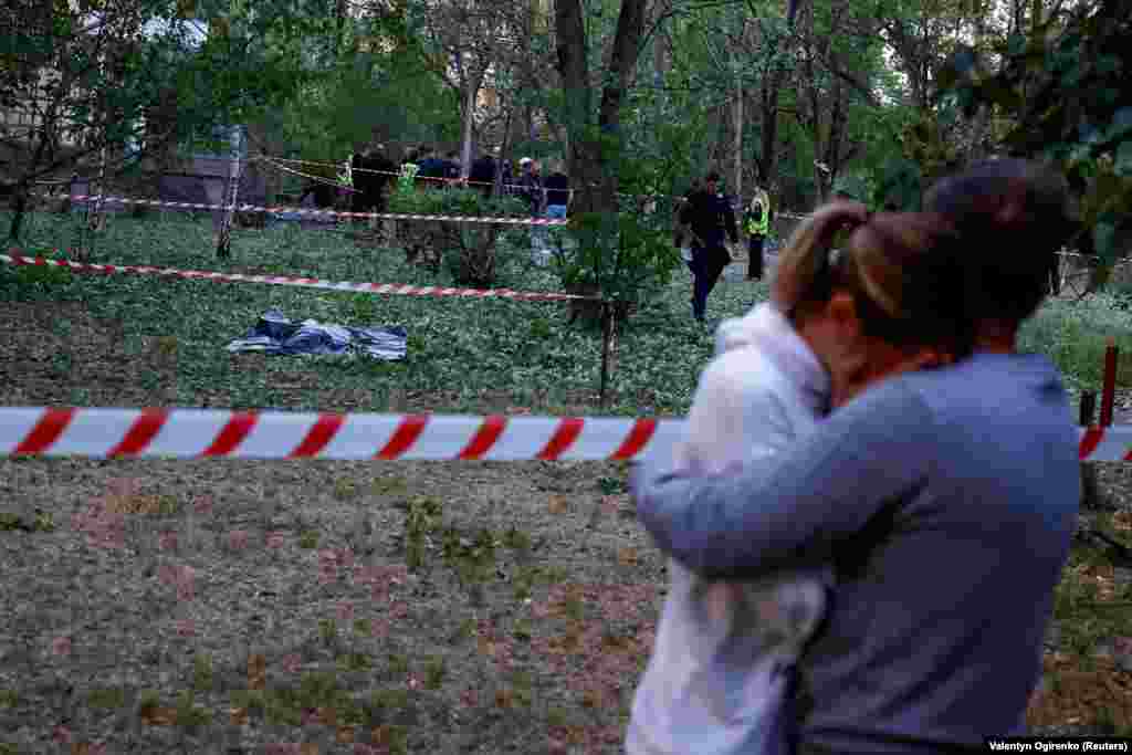 A man comforts a woman near the body of a person killed by falling debris near a municipal clinic. At least three people were killed in the attack, according to local officials. Ukraine's air force said air defenses shot down all 10 ballistic and Iskander cruise missiles launched from Russia's Bryansk region in the 18th attack on the capital since the start of May.