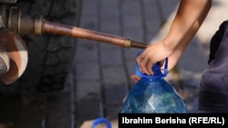 Një person duke mbushur një bidon me ujë.