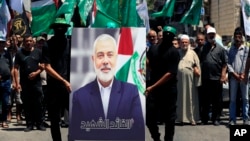 ჰამასის წევრებს უჭირავთ წინა ღამეს მოკლული ლიდერის, ისმაილ ჰანიეს ფოტო, რომელსაც არაბულად აწერია "მოწამე ლიდერი", ალ-ბასის პალესტინელ ლტოლვილთა ბანაკი, ლიბანი, 2024 წლის 31 ივლისი