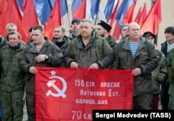 Recruții și voluntarii ruși mobilizați țin steagul victoriei sovietice în timp ce se pregătesc să plece din Orenburg, Rusia, în octombrie 2022.