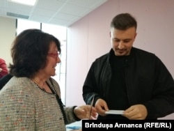 Adrian Ghenie privind fotografia unei lucrări de tinerețe, Autoportret cu frunză, colecționată de o scriitoare din Cluj