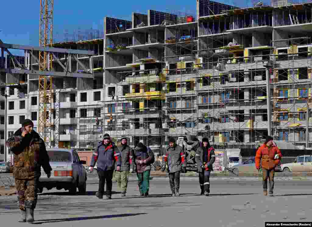 Workers at the site of a construction project in Mariupol. According to the UN, up to 90 percent of the city's residential buildings were damaged or destroyed during the Russian siege.&nbsp;
