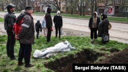 Жители Мариуполя хоронят прямо на улице своего погибшего соседа, апрель 2022 года