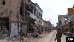 پاکستاني پوځيان د ميرامشا په وران کړي بازار کې ولاړ دي. د ۲۰۱۴ کال د جولای د میاشتې انځور.