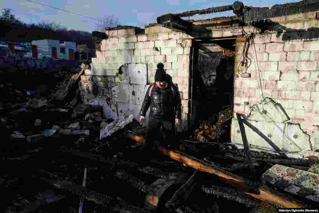 Місцева жителька Оксана Кобзаренко оглядає свій будинок і подвір'я, як повідомила влада, пошкоджені під час російського удару безпілотниками у селі Старі Безрадичі Київської області, 19 грудня 2022 року