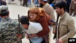 په تورخم کې يو افغان خپله ناروغه مور په شا کړې ده. يو پاکستاني پوځي یې اسناد ګوري (تصویر له ارشيفه)