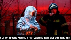 Украинанын куткаруу жана өрт өчүрүү кызматынын өкүлдөрү Львовдогу орус күчтөрү сокку урган кара май кампасындагы өрттү өчүрүүгө аракет кылып жатат. 26-март,  2022-жыл. 