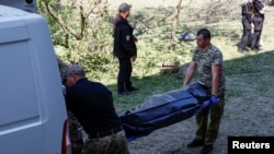 Medicii legiști urcă într-o ambulanță cadavrul unei fete ucise în timpul unui atac cu rachete rusești.