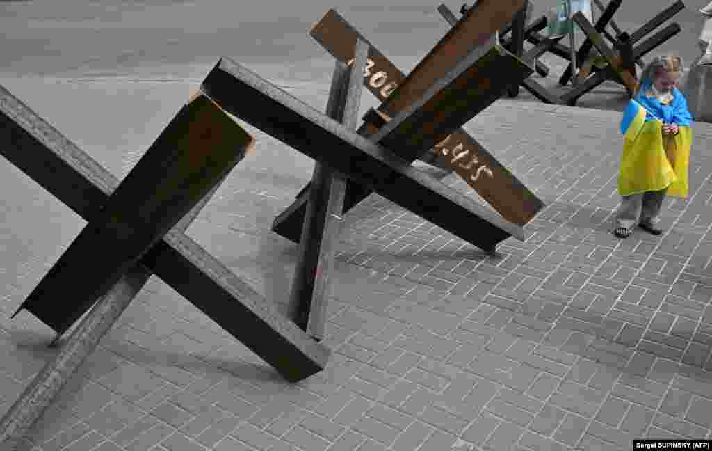 Дете носи украинско знаме за време на митингот &bdquo;Спасете ја војската во Мариупол&ldquo; во Киев на 3 мај. Митингот беше организиран за поддршка на заробениот баталјон Азов, кој се засолни со цивили во бункерите под челичарницата Азовстал. Руските трупи го продолжија нападот врз централата по пауза што овозможи евакуација на некои цивили. &nbsp;