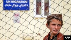 په کندهار کې هېواد ته ستون شوی افغان ماشوم د مهاجرت نړیوال سازمان د نوملیکنې د مرکز مخې ته ولاړ دی - د اپرېل اوومۍ انځور.