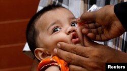 یو روغتیايي کارکوونکی په پاکستان کې ماشوم ته د پولیو څاڅکي ورکوي - پخوانی انځور.