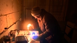 O femeie aprinde o lumânare în apartamentul ei dintr-un bloc de locuințe, distrus parțial după bombardamentele rusești. Foto: Serghei Șuzavkov / AFP)