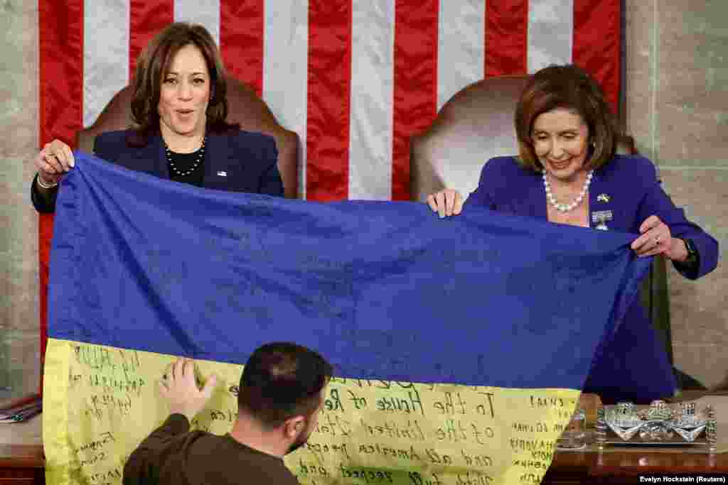 U.S. Vice President Kamala Harris (left) and U.S. House Speaker Nancy Pelosi hold an inscribed Ukrainian flag brought by Zelenskiy from Bakhmut. In his address, Zelenskiy compared the heroism of Ukrainian soldiers defending Bakhmut to that shown by U.S. troops fighting Adolf Hitler&rsquo;s troops in the Battle of the Bulge in 1944, also during the Christmas season. "Bakhmut stands," Zelenskiy said to cheers. "Ukraine holds its lines and will never surrender."