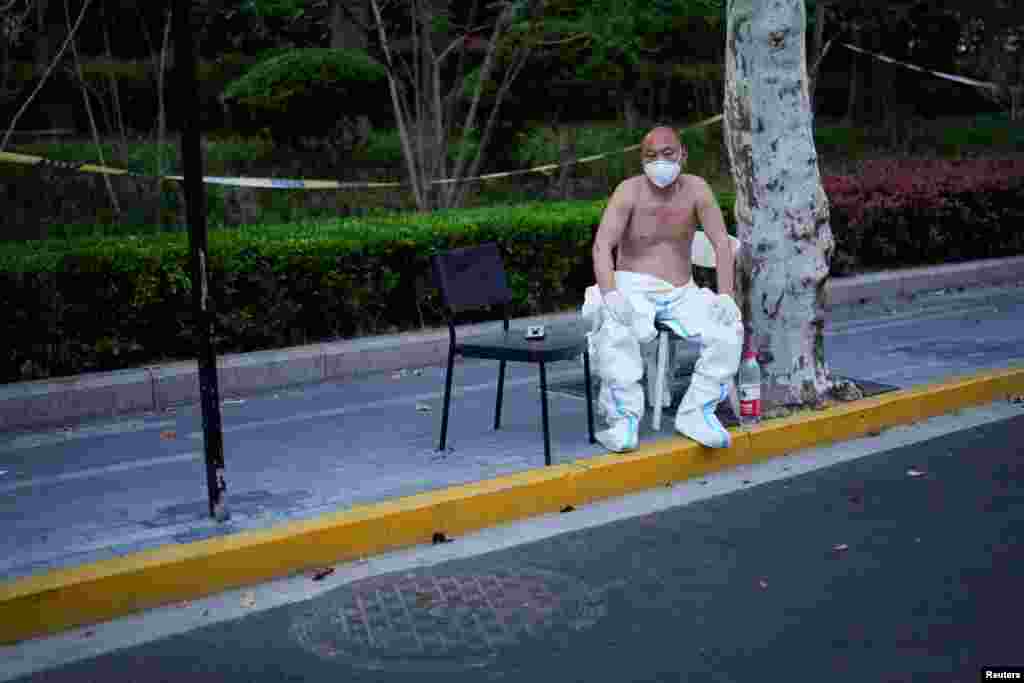 Një punëtor me veshje mbrojtëse duke pushuar përjashta, Shangai, Kinë 11 prill.